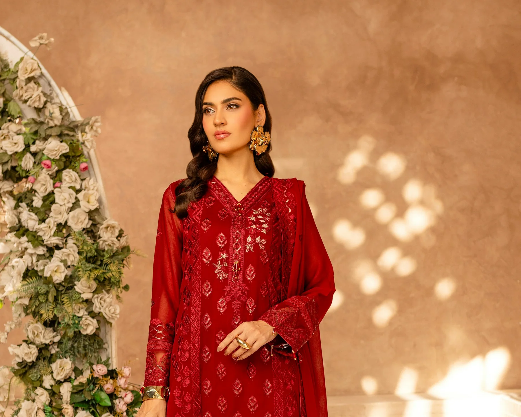 Woman in a red embroidered festive shalwar kameez with a dupatta